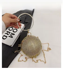 Dettaglio della borsa da sera sferica dorata con strass e manico circolare in metallo