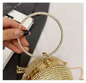Dettaglio di una lussuosa pochette a sfera con strass dorati e manico circolare in metallo