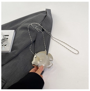 Detailed view of silver fish-shaped clutch bag with scale texture and beaded chain strap