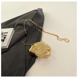 Detailed view of the fish-shaped golden metal clutch with textured scales and fine chain