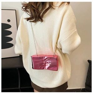 Detail of hot pink metallic textured box bag with chain strap on beige sweater