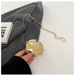 Detail of golden fish-shaped mini metal purse with bead chain and scale texture
