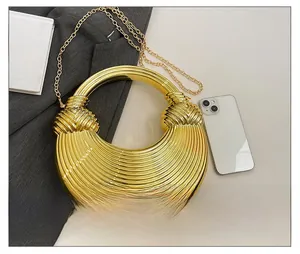 Détail d'une pochette dorée ronde avec texture ondulée et fine bandoulière chaîne