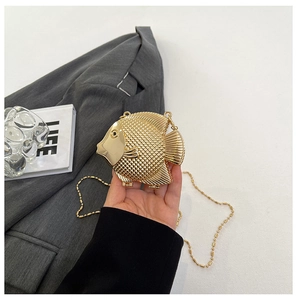 Detailed view of fish-shaped gold evening bag with metallic texture and bead chain