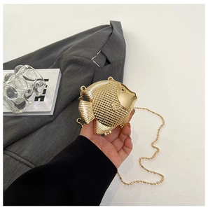 Detailed view of fish-shaped gold metal clutch with intricate scale texture and chain strap
