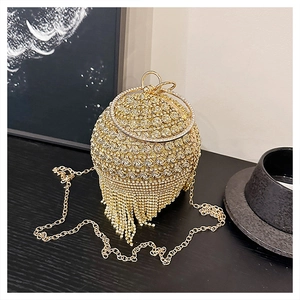 Dettaglio macro della pochette sferica dorata con strass luccicanti e lunghe frange