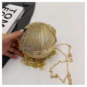 Dettaglio della pochette sferica dorata con strass scintillanti ed eleganti nappe