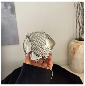 Close-up of a creative silver fish-shaped mini handbag with metallic woven texture and chain