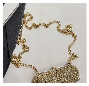 Detail of the golden evening bag featuring sparkling rhinestones and a delicate metal chain