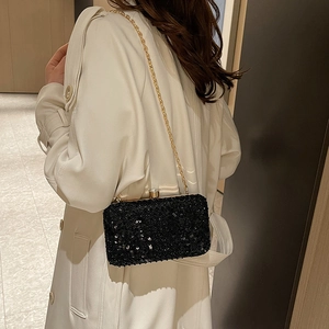 Elegant black beaded evening bag with sequins and gold chain strap worn by a model