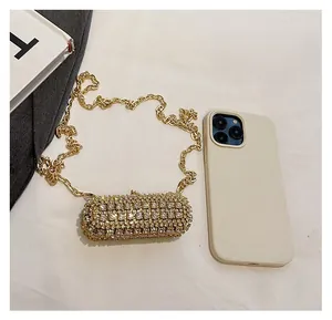 Size comparison of a mini rhinestone evening bag next to a smartphone and book