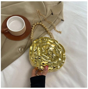 Close-up of golden rose-shaped evening bag with layered petals and beaded chain handle