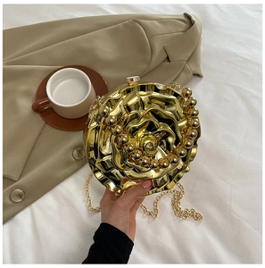 Detail of golden 3D rose flower evening clutch bag with metallic finish and chain strap