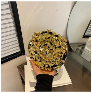 Detail of rose-shaped gold metal evening bag with floral texture and pearl handle