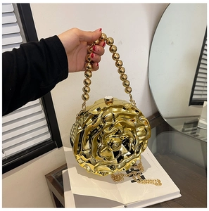 Detail of golden 3D rose-shaped acrylic handbag with metallic beaded handle and long chain