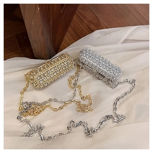Detail of silver and gold rhinestone mini lipstick bags with long metal chain straps