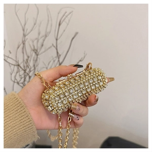 Detailed view of mini cylindrical rhinestone clutch bag with gold chain strap in hand