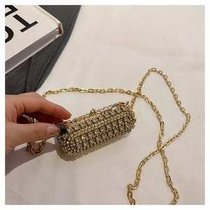 Detail of a luxury mini cylinder evening bag with white rhinestones and a gold chain strap
