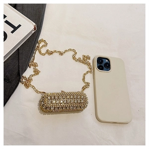Macro shot of mini gold rhinestone evening bag with chain strap next to a phone