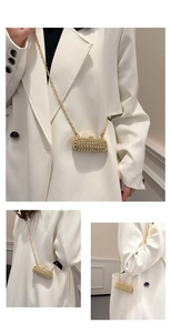 Macro view of capsule-shaped rhinestone evening bag with elegant gold chain strap