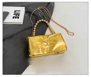 Pochette metallica dorata con trama a pieghe, manico a perle e tracolla a catena dorata