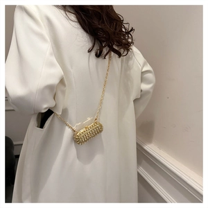 Detailed view of luxury gold pill-shaped evening bag with sparkling rhinestones and chain