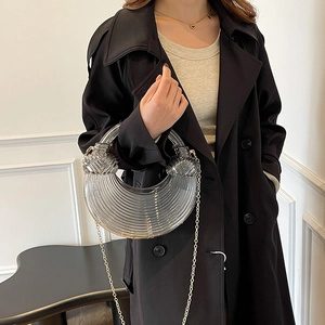 Sac croissant en acrylique avec texture annelée et chaîne dorée sur mannequin en manteau