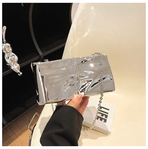 Dettaglio della borsa clutch in acrilico argento con trama a pieghe e tracolla a catena