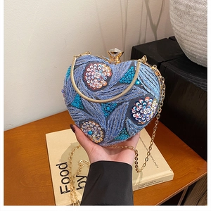 Detailed embroidery of floral sequins on a heart-shaped evening clutch bag with crystal clasp
