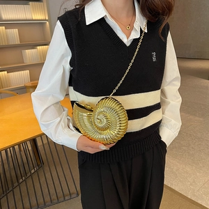 Elegant gold shell evening clutch bag with spiral metallic texture and chain strap on model