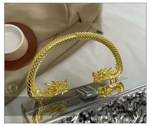 Close-up of golden dragon handle and silver textured finish on acrylic evening box bag