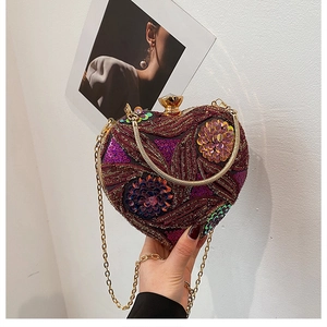 Macro shot of heart-shaped evening bag with purple floral sequins and gold chain