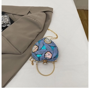 Detail of heart-shaped evening bag featuring floral sequin embroidery and gold round handle