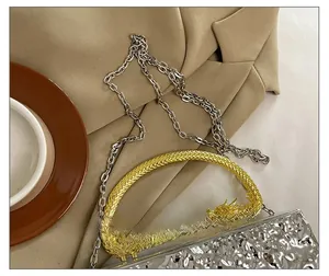 Detailed shot of golden dragon handle and silver textured acrylic evening clutch bag