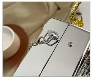 Detail of silver acrylic mirror clutch featuring a gold dragon handle and hardware
