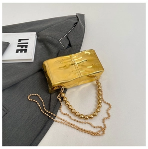 Dettaglio della borsa clutch in acrilico dorato con manico di perle e finitura in metallo