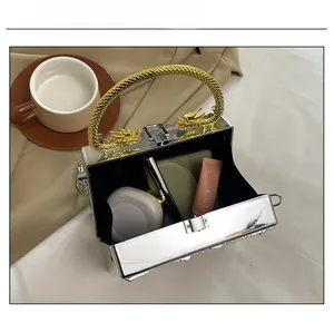 Mirror silver acrylic box bag showing interior capacity for cosmetics and gold dragon handle