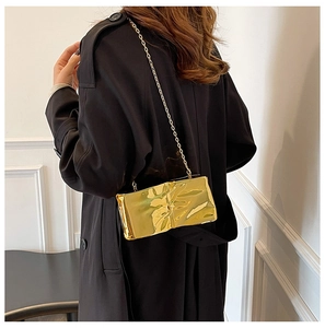 Dettaglio di una borsa rettangolare dorata metallizzata con sottile tracolla a catena