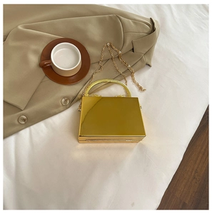 Detailed view of golden acrylic mirror box bag with metal handle and chain strap