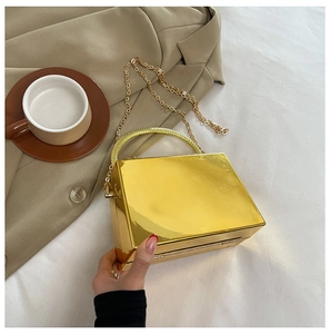 Detail of mirror gold box clutch with a sparkling rhinestone top handle and chain strap