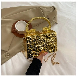 Detail of gold box clutch featuring liquid metal texture and ornate dragon head handles