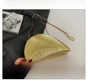 Detail of a golden seashell-shaped evening clutch bag with intricate ribbed metal texture