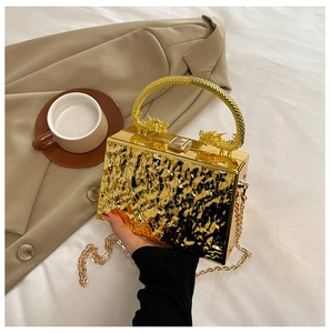 Detail of gold box clutch with dragon handle and ripple texture for evening party