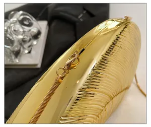 Macro detail of golden conch shell evening bag featuring radial textures and sleek metal chain