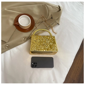 Detailed size comparison of a gold metallic evening bag next to a smartphone