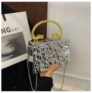 Detail of silver mirror box clutch with golden double dragon handle and wave texture