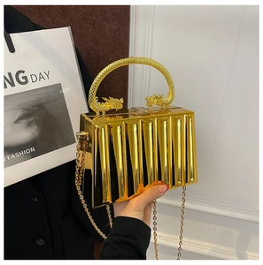 Detail of gold acrylic clutch with vertical wave texture and dragon-shaped top handle