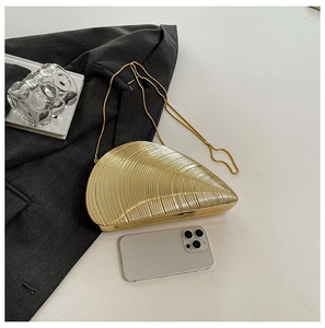 Detailed view of a gold conch shell acrylic evening bag with metallic chain and texture