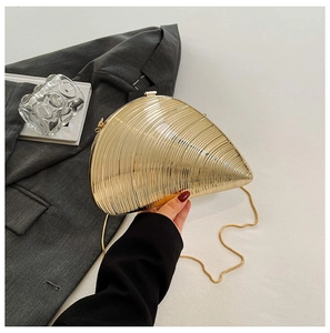 Close-up of gold conch-shaped evening bag with ribbed metal texture and gold chain strap