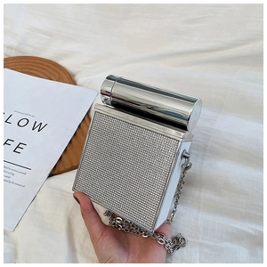 Close-up of sparkling silver rhinestone chain bag with elegant cylindrical metal handle